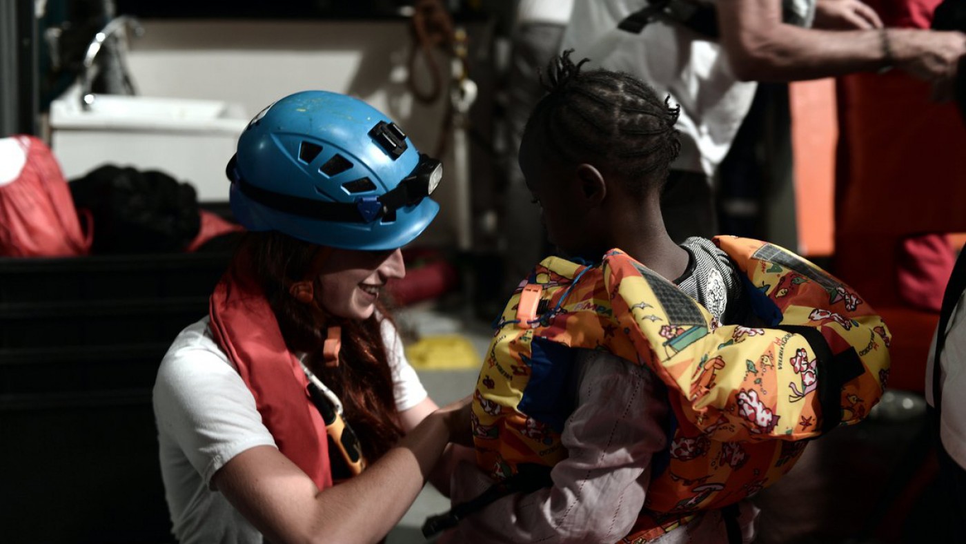 una voluntaria de ong atiende a uno de los niños que viajan en el barco