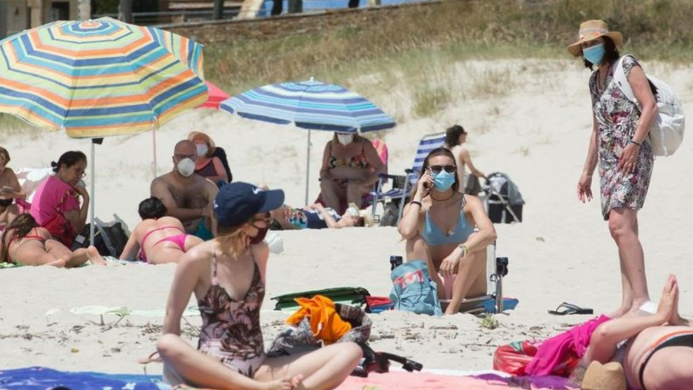 Gente con mascarilla en la playa