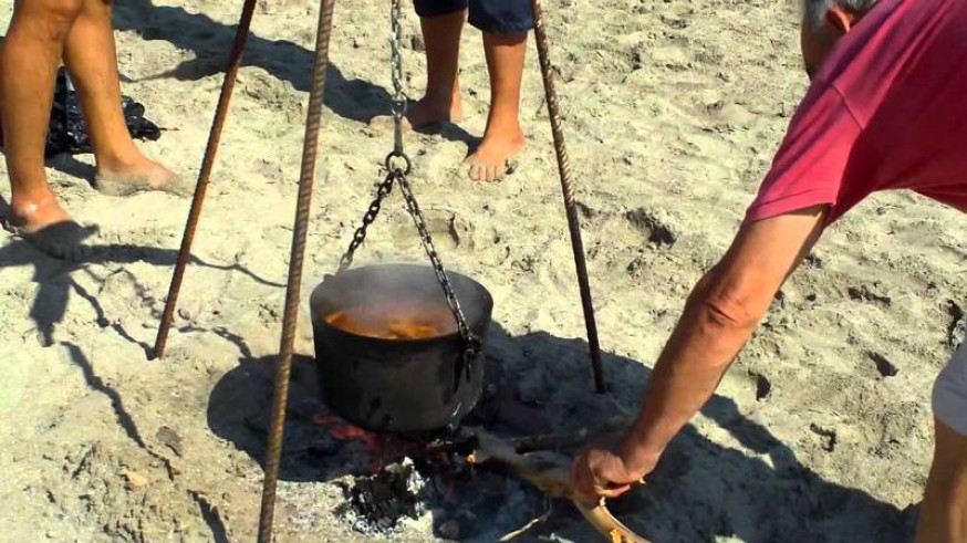 Personas cocinando un caldero en la playa