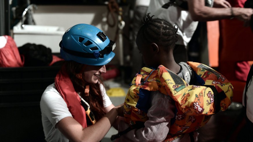 una voluntaria de ong atiende a uno de los niños que viajan en el barco