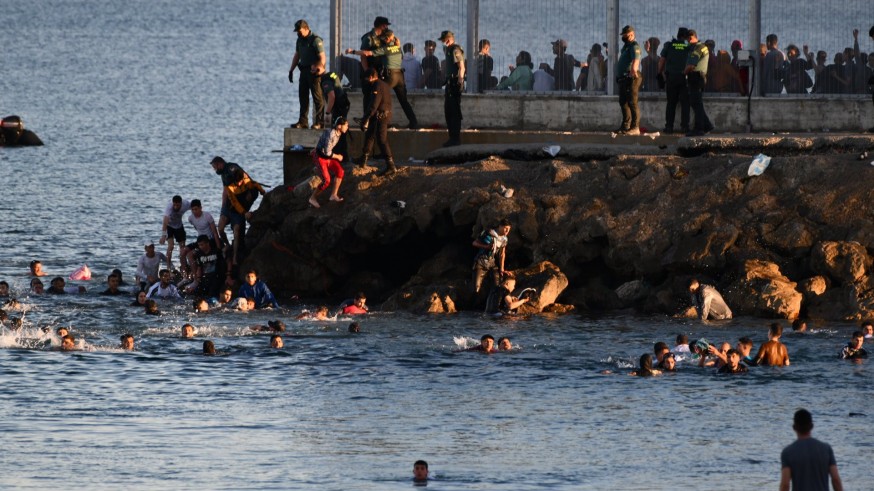 Personas migrantes en la playa del Tarajal se lanzan al mar para entrar en Ceuta.