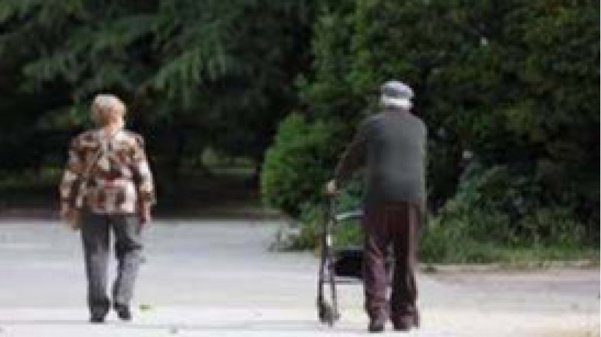 Una mujer y un hombre de edad avanzada con andador paseando