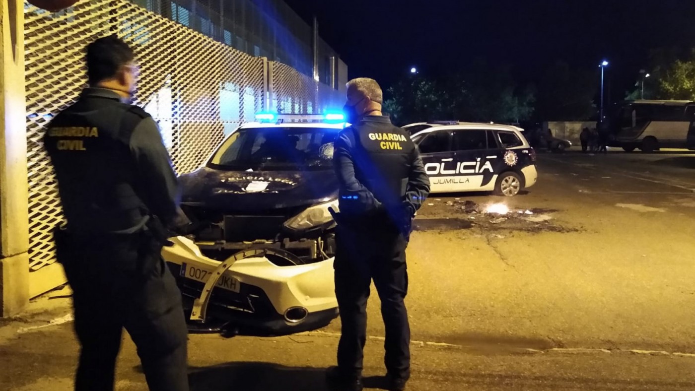 Agentes de la Guardia Civil contemplan los destrozos de dos vehículos policiales en Jumilla
