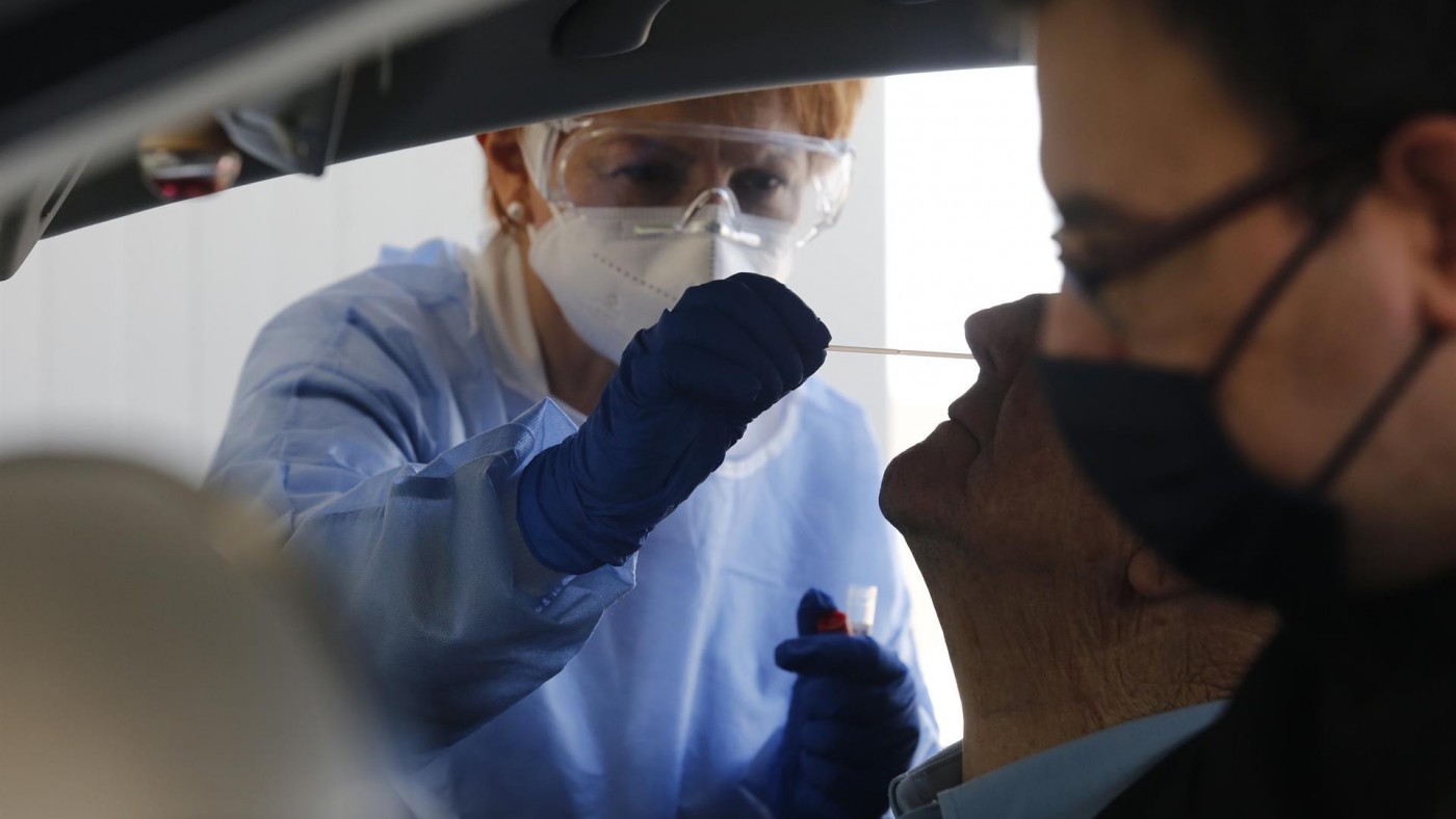 Una enfermera toma muestras para una PCR a un paciente en un coche