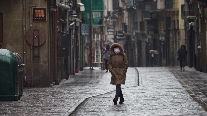 Una mujer camina protegida con una mascarilla por la Calle Estafeta
