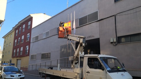 Operario bajando bandera a media asta en la sede de la policía local de Totana. Foto S.López