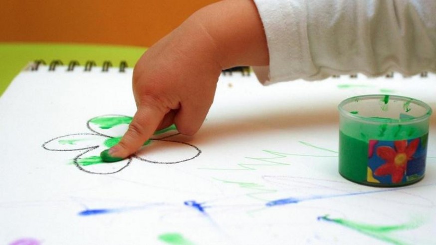 Un bebé pinta con los dedos en una escuela de educación infantil