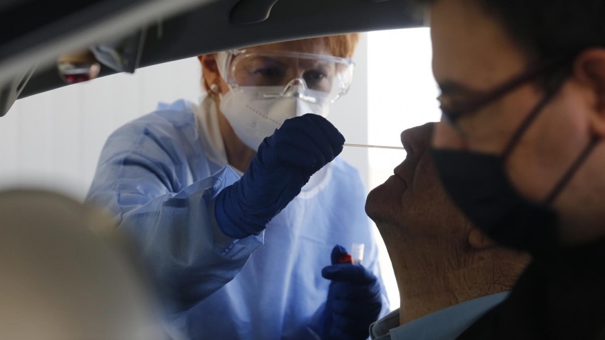 Una enfermera toma muestras para una PCR a un paciente en un coche