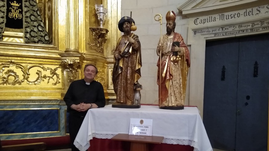 El párroco de la iglesia de Santiago en Jumilla junto a las imágenes restaurada del retablo 