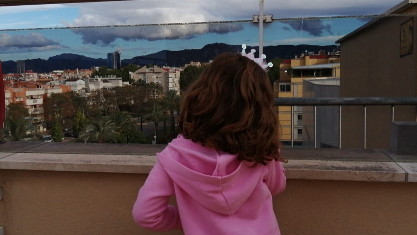 Una niña mirando la calle desde el balcón. ORM