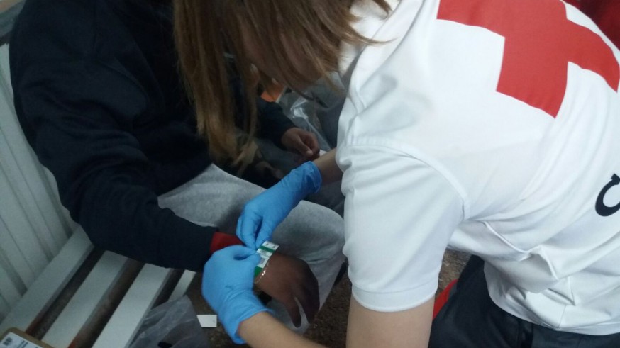 Un miembro de Cruz Roja atiende a uno de los inmigrantes llegados en patera