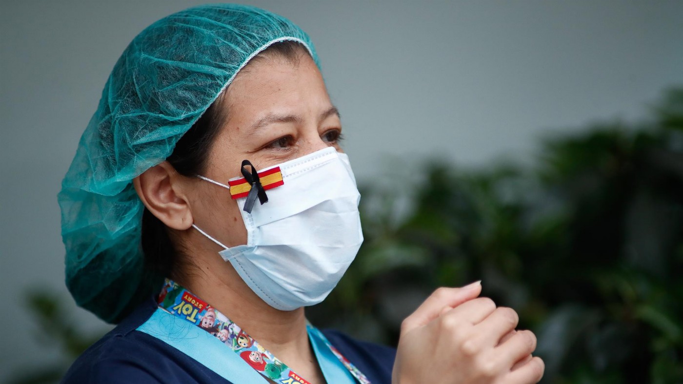 Una sanitaria, con una mascarilla que muestra una bandera de España con un lazo negro de luto por los fallecidos por coronavirus
