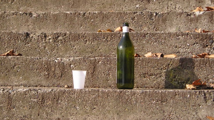 Botella vacía abandonada en unos escalones