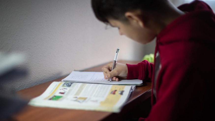 Estudiante haciendo deberes delante de un libro