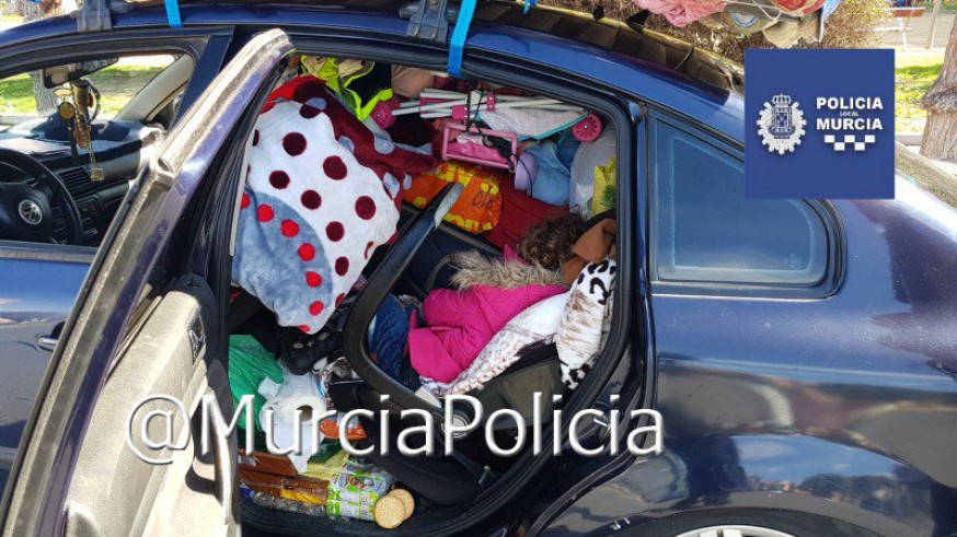 Niña atrapada entre los enseres del coche