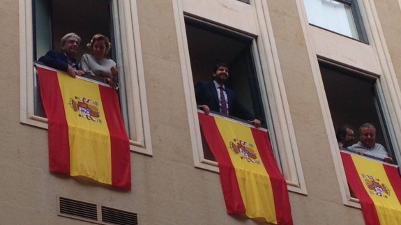López Miras, junto a otros miembros del PP, cuelga las banderas de España en la sede de esta formación