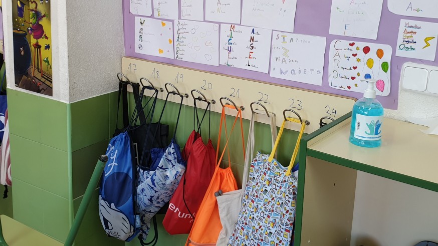 Gel hidroalcohólico junto al perchero para las mochilas en un aula. ORM