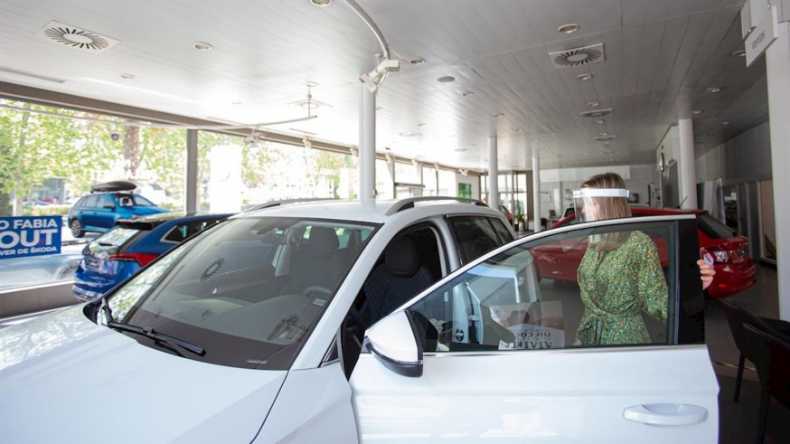 Una compradora con pantalla protectora mira coches en un concesionario